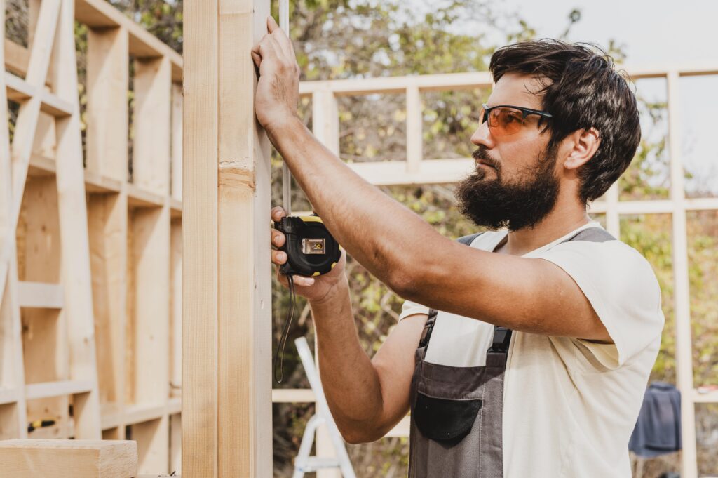 Contractor measuring an existing house during a site investigation